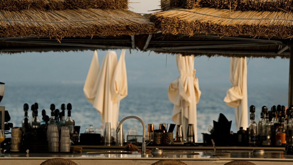 Strandbar met rieten dak, barkrukken en uitzicht op zee