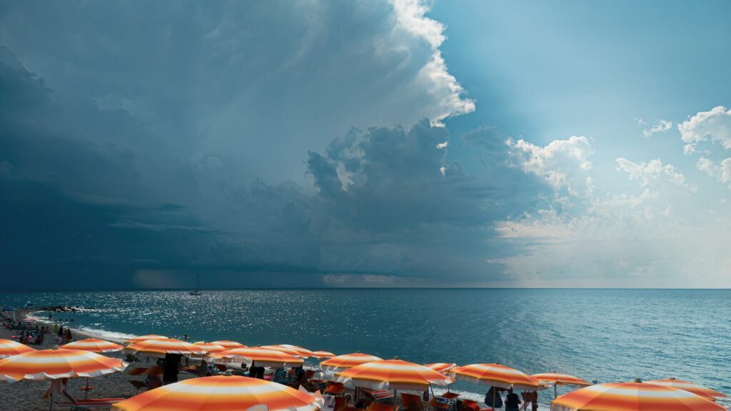 Strand met oranje parasols en een naderende onweersbui boven zee