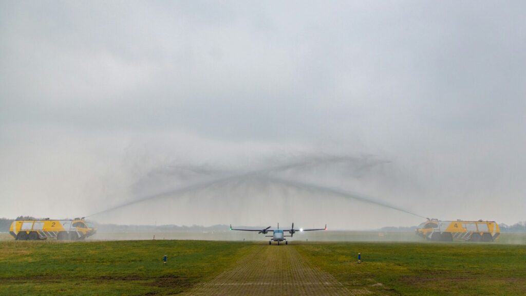 Vliegtuig landt op Groningen Airport Eelde, begroet met een watergroet van brandweerwagens